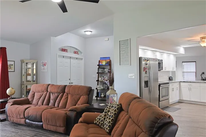 Living area featuring ceiling fan, light wood-type flooring, and lofted ceiling