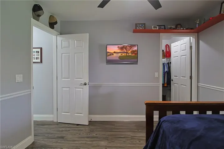 Bedroom with a walk in closet, dark wood-style floors, and a ceiling fan