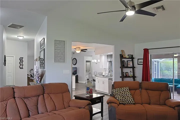 Living area with ceiling fan, vaulted ceiling, and light wood-type flooring