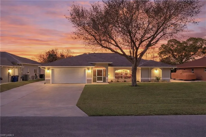 Ranch-style home with concrete driveway, a garage, a yard, and stucco siding