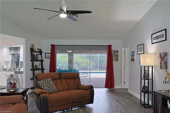 Living area featuring a ceiling fan, dark wood-type flooring, and vaulted ceiling