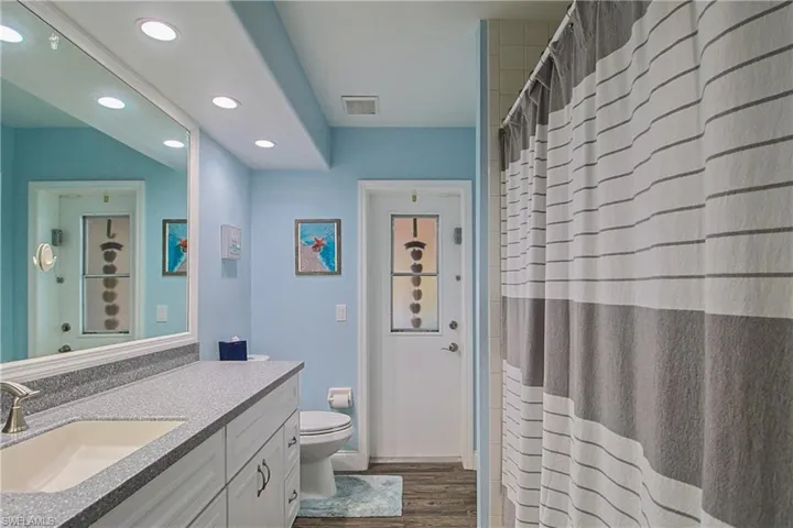 Full bathroom with vanity, a shower with shower curtain, dark wood-style flooring, and recessed lighting