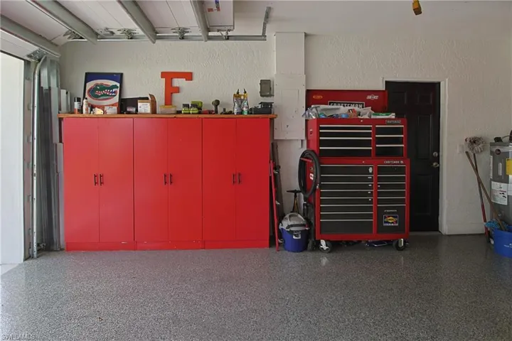 Garage with a textured wall, water heater, and a workshop area