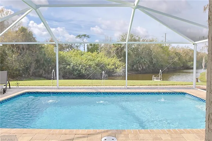 Outdoor pool featuring a lanai, a yard, and a water view