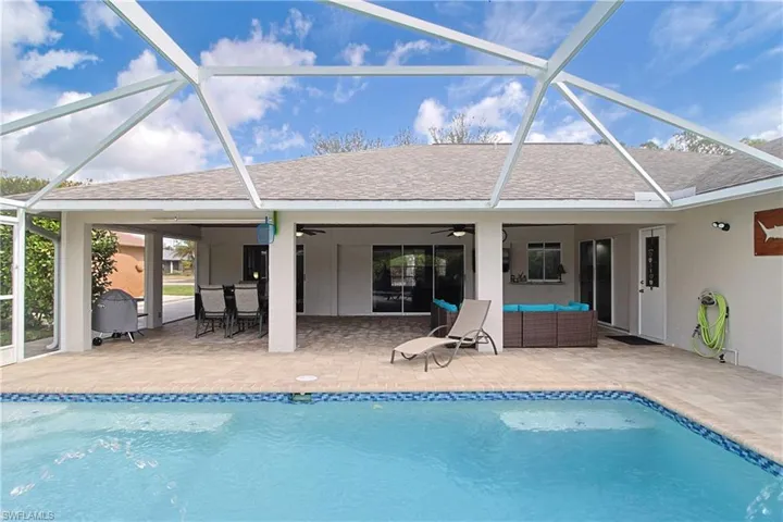 Outdoor pool with a sunroom, glass enclosure, and a patio
