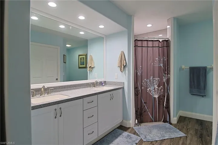 Bathroom featuring double vanity, a shower with shower curtain, dark wood-type flooring, and recessed lighting