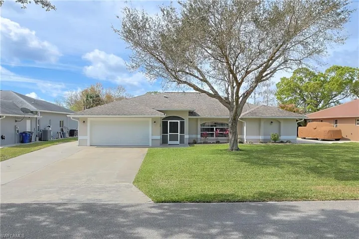 Ranch-style home with stucco siding, a garage, driveway, a front lawn, and roof with shingles