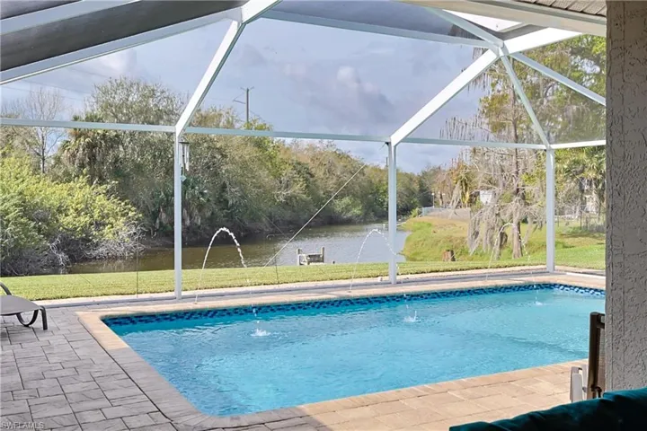Outdoor pool featuring a sunroom, glass enclosure, and a lawn