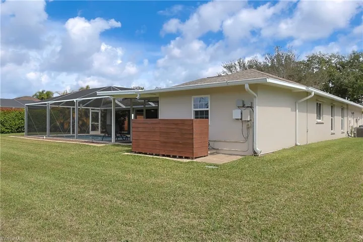 Back of property featuring stucco siding, glass enclosure, a swimming pool, a patio, and a yard