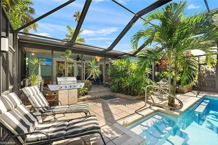 Outdoor pool featuring a patio area, ceiling fan, glass enclosure, and area for grilling
