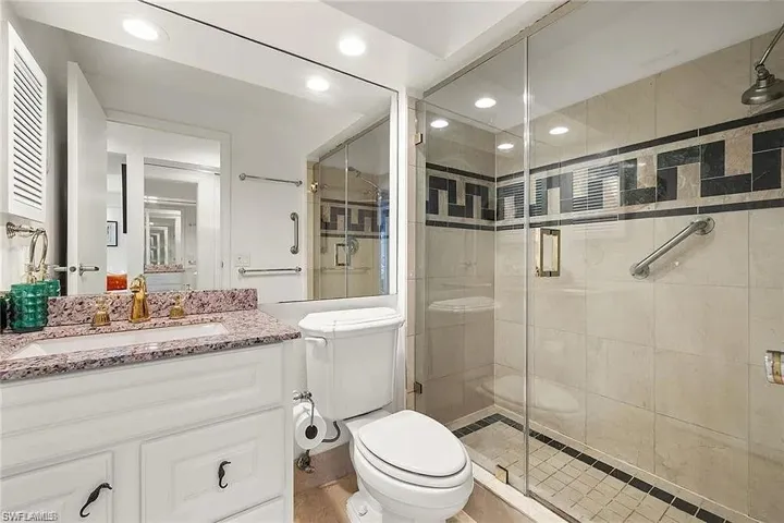 Bathroom featuring toilet, a stall shower, vanity, and recessed lighting