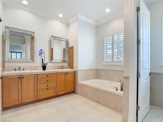 Full bathroom with ornamental molding, a bath, double vanity, light tile patterned floors, and recessed lighting