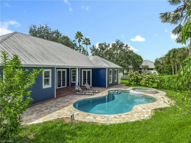 View of pool featuring french doors, a patio, a pool with connected hot tub, and a lawn