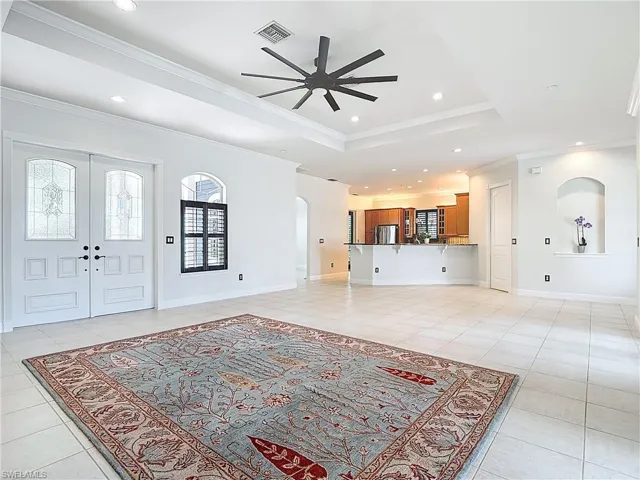 Entrance foyer featuring a tray ceiling, healthy amount of natural light, light tile patterned flooring, a ceiling fan, and ornamental molding