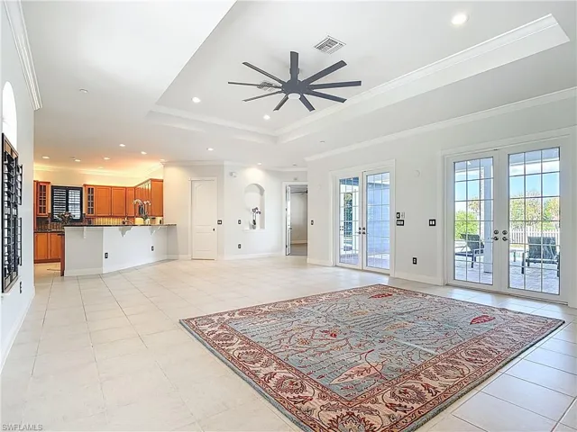Living room with french doors, a tray ceiling, ornamental molding, recessed lighting, and a ceiling fan