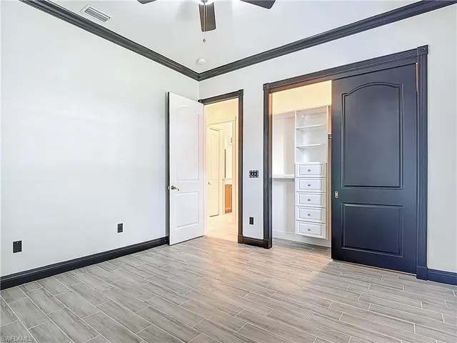 Unfurnished bedroom with crown molding, a ceiling fan, wood tiled floors, and a closet