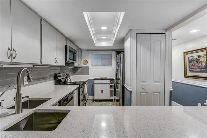 Kitchen with stainless steel appliances, light stone countertops, backsplash, and recessed lighting