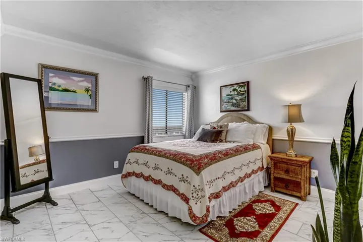 Bedroom featuring light marble finish flooring and ornamental molding