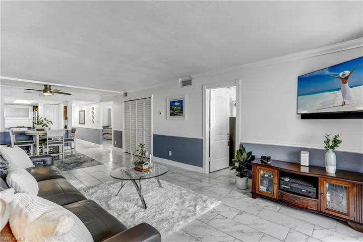 Living area featuring a ceiling fan and light marble finish floors