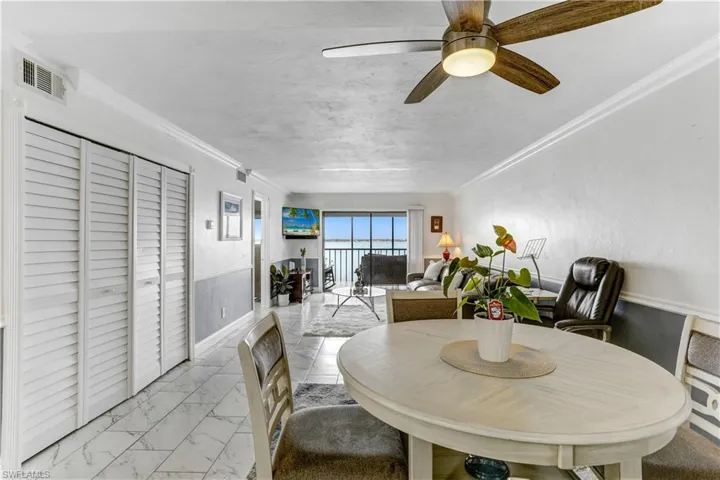 Dining room featuring a ceiling fan, light marble finish floors, and crown molding