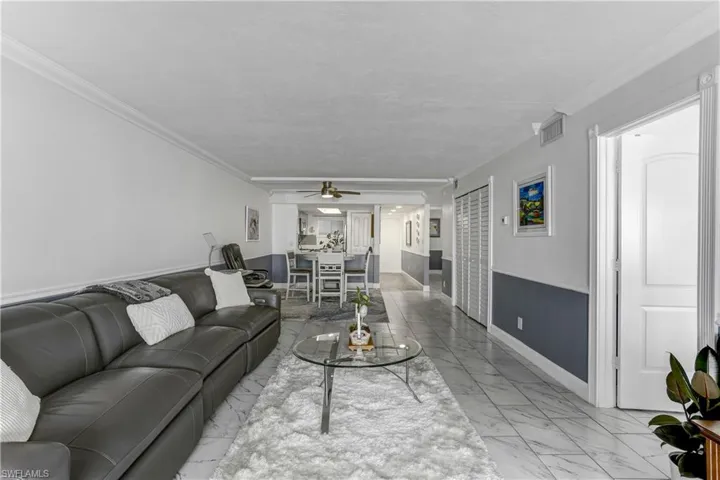 Living area with light marble finish floors, crown molding, and ceiling fan