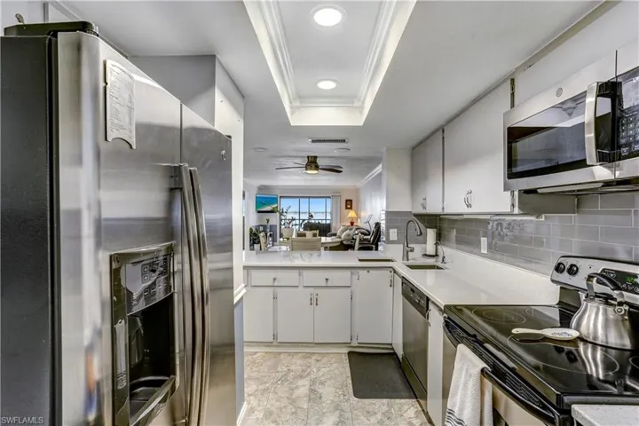 Kitchen with crown molding, stainless steel appliances, tasteful backsplash, ceiling fan, and a peninsula