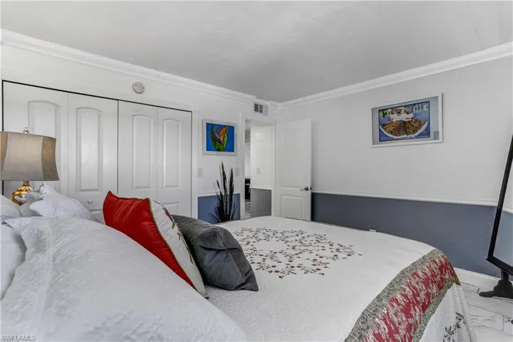 Bedroom featuring a closet, crown molding, and light marble finish floors