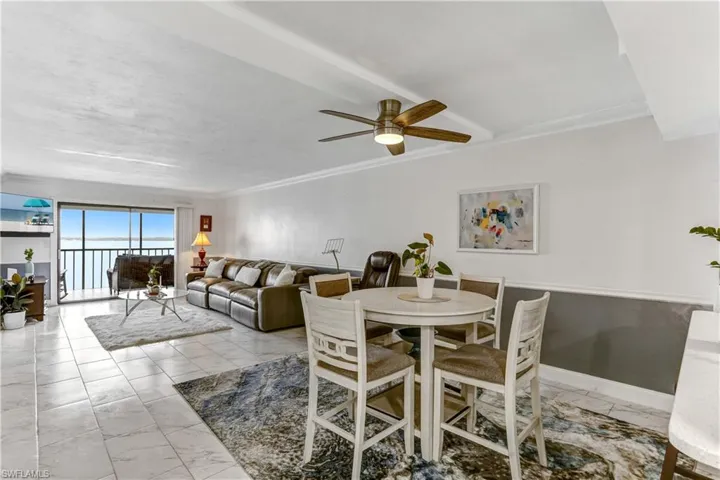Dining space featuring ceiling fan, light marble finish floors, and crown molding