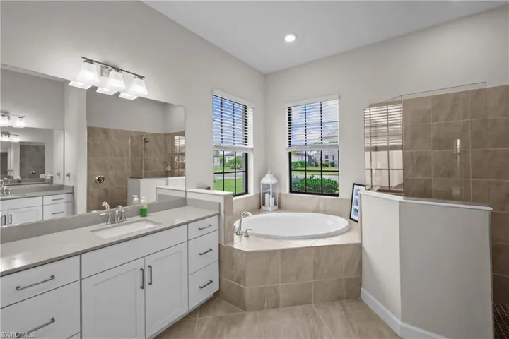 Bathroom with a sink, two vanities, a bath, tile patterned flooring, and walk in shower