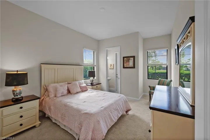 Bedroom with light colored carpet, ensuite bath, and baseboards
