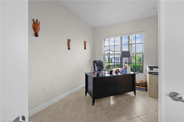 Office or fourth bedroom featuring baseboards, light tile patterned floors, and vaulted ceiling