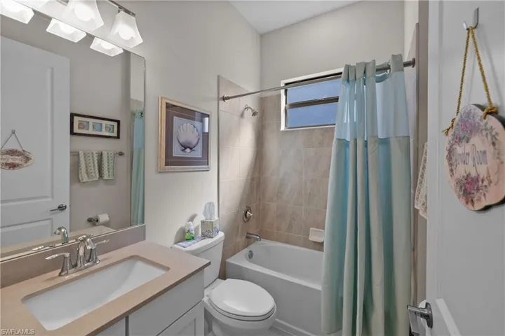 Full bathroom with vanity, shower / bathtub combination with curtain, and toilet