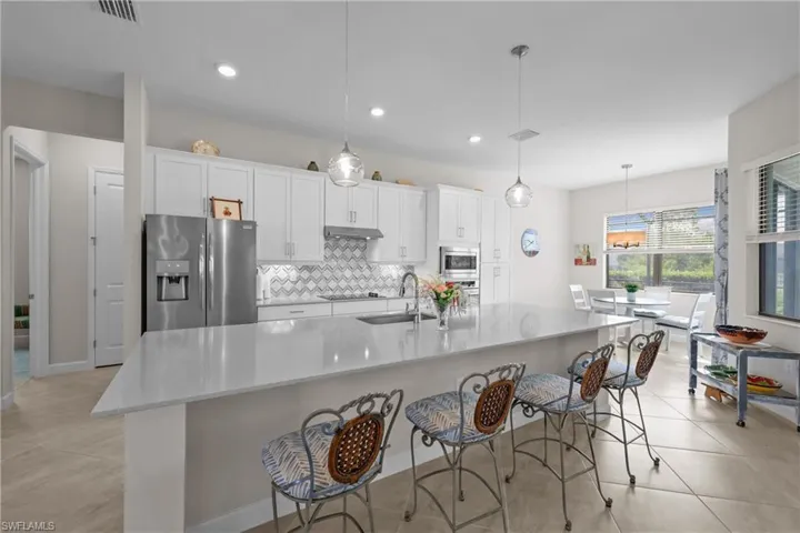 Kitchen with a sink, stainless steel appliances, visible vents, backsplash, and under cabinet range hood