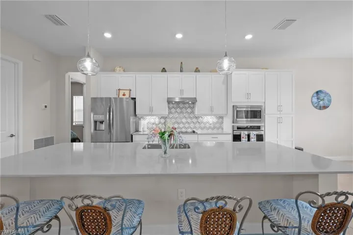 Kitchen featuring a spacious island, white cabinetry, a kitchen breakfast bar, stainless steel appliances, and tasteful backsplash