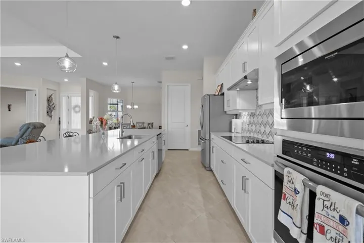 Kitchen with backsplash, light countertops, stainless steel appliances, and a sink