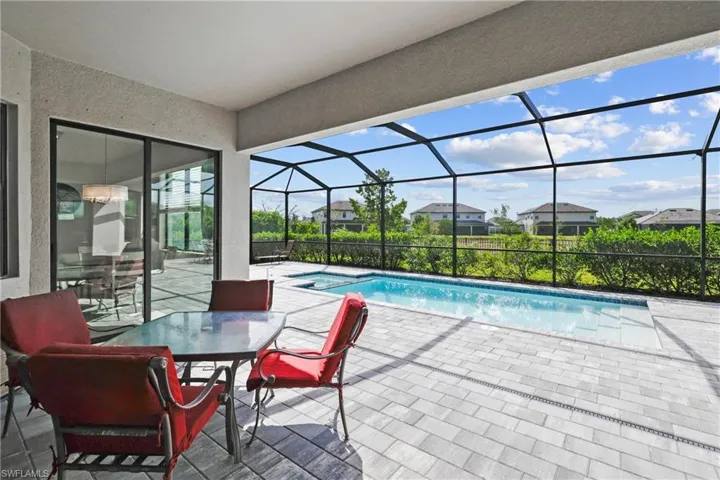 View of swimming pool featuring a pool with connected hot tub, a patio, a lanai, and a residential view