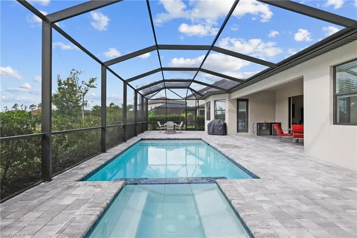 View of pool featuring a patio area, a pool with connected hot tub, and glass enclosure
