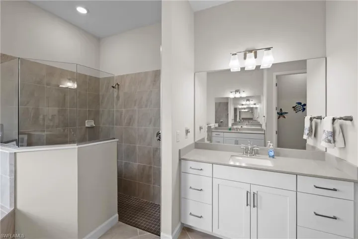 Bathroom with vanity, a walk in shower, and tile patterned floors