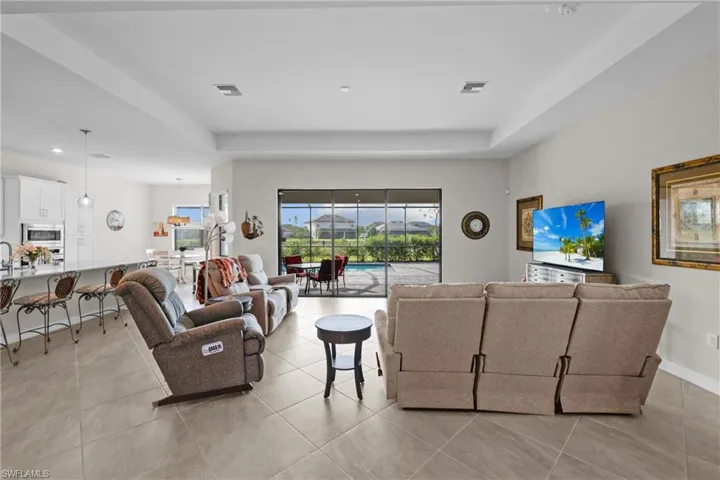 Living area featuring a raised ceiling, light tile patterned floors, and recessed lighting