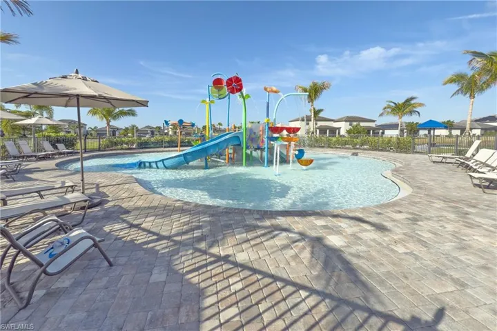 Community jungle gym with a water play area, a community pool, a patio, and fence
