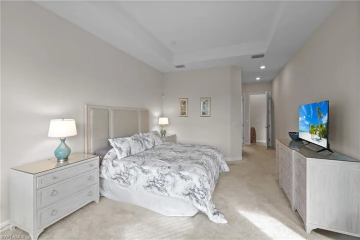 Bedroom with visible vents, recessed lighting, light carpet, a raised ceiling, and baseboards