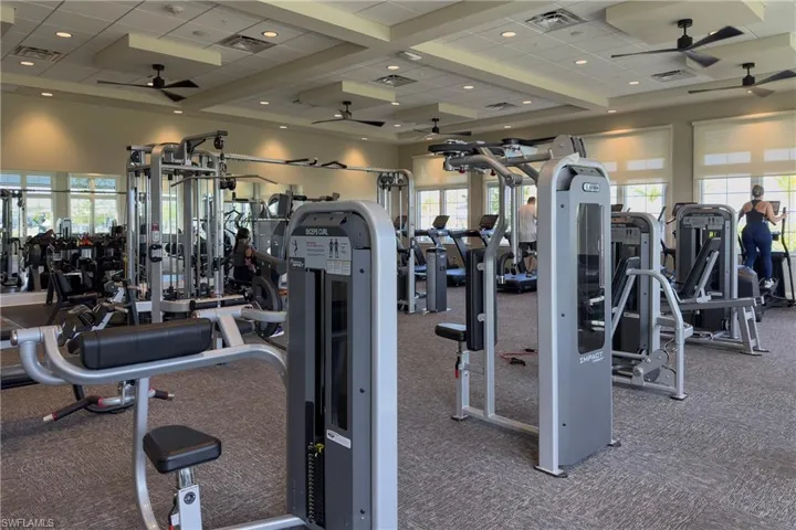 Exercise room with coffered ceiling, ceiling fan, carpet floors, and visible vents