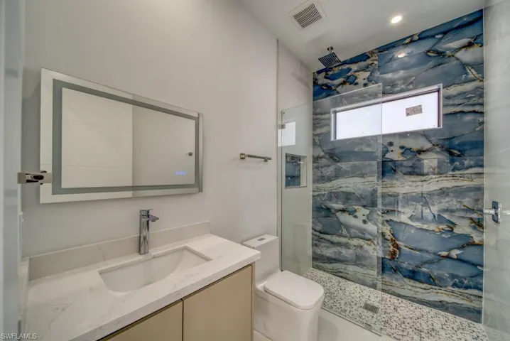Full bathroom featuring a marble finish shower and vanity