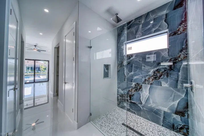Full bathroom with a ceiling fan, healthy amount of natural light, a marble finish shower, and recessed lighting