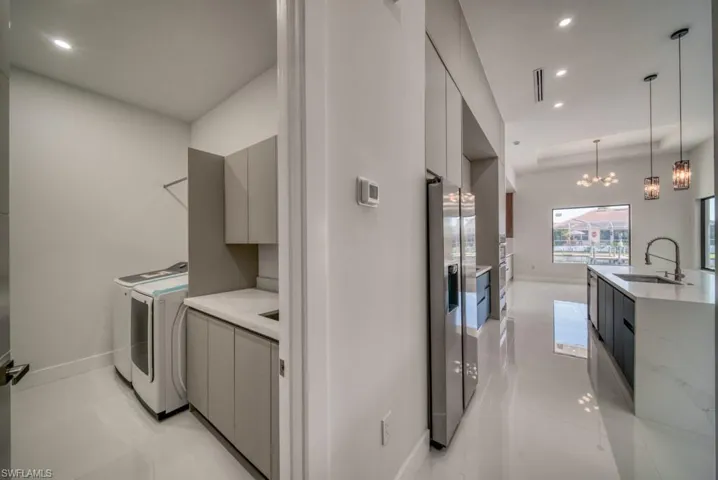 Washroom with recessed lighting, a chandelier, cabinet space, and washer and dryer