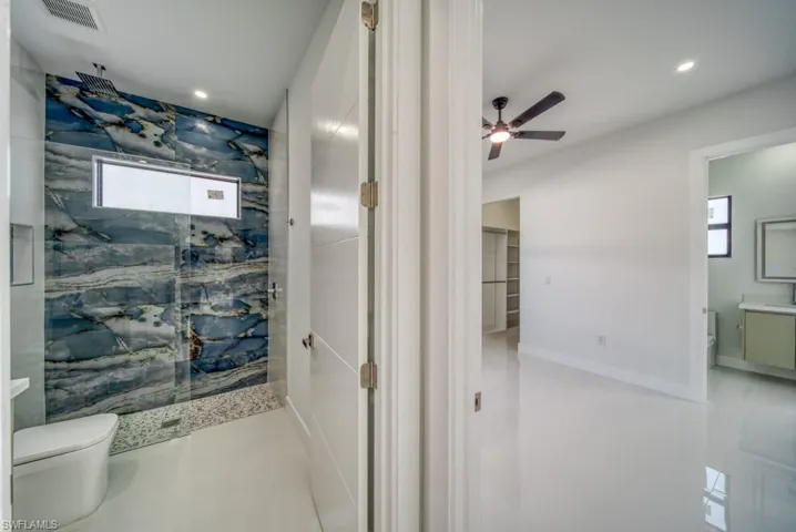 Bathroom with a marble finish shower, vanity, ceiling fan, and recessed lighting