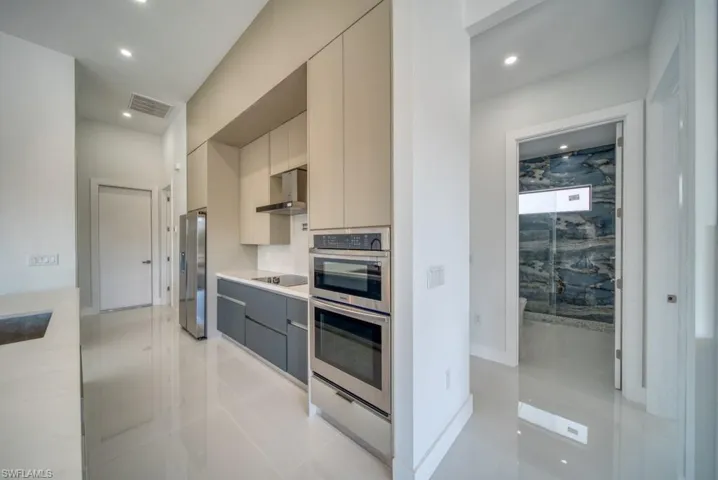 Kitchen featuring modern cabinets, recessed lighting, cream cabinetry, appliances with stainless steel finishes, and gray cabinets