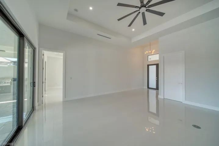 Empty room with a raised ceiling, light tile patterned flooring, recessed lighting, and ceiling fan