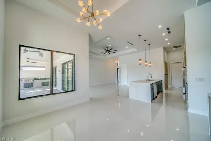 Unfurnished living room with a raised ceiling, a ceiling fan, recessed lighting, and a chandelier