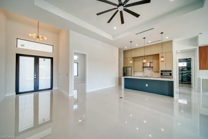 Kitchen with open floor plan, modern cabinets, a chandelier, a raised ceiling, and hanging light fixtures